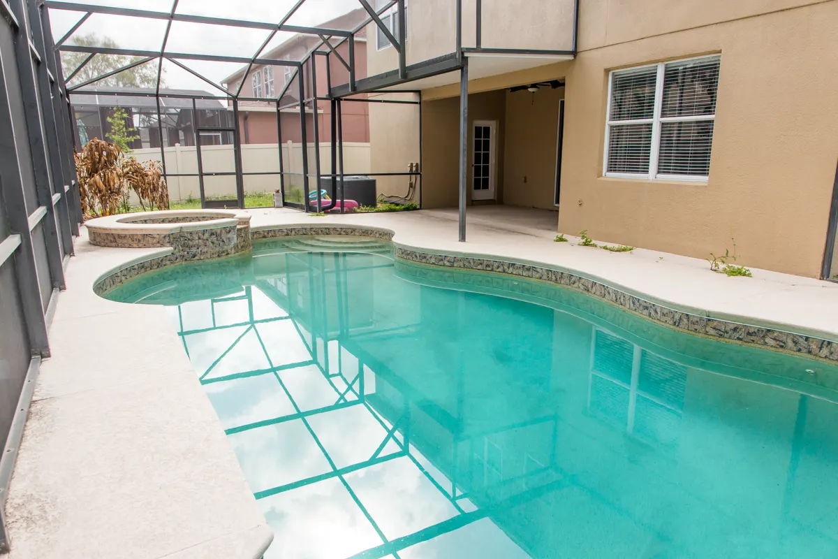Current condition: wide view of the screened pool sweeping toward the raised spa and covered lanai.