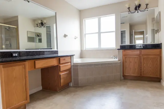 Current condition primary bathroom with soaking tub, shower, and wood vanity.