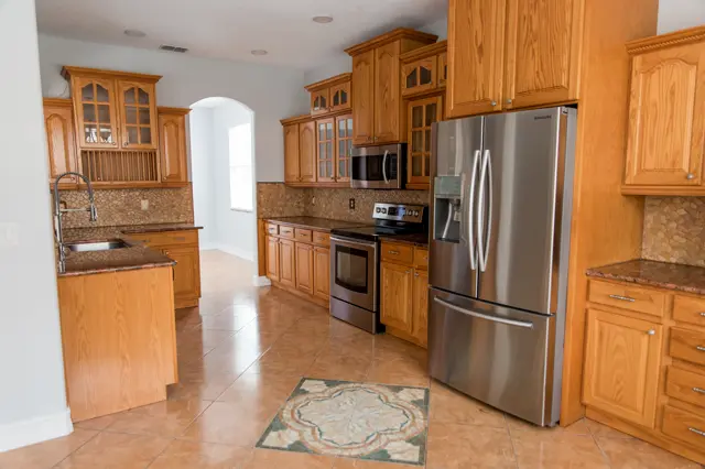 Current condition kitchen with wood cabinetry, granite countertops, and stainless-steel appliances.